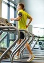 Man with smartphone exercising on treadmill in gym Royalty Free Stock Photo