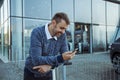 Man with smartphone in front of the glass facade