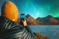 Man with smartphone taking photo of northern lights winter travel in Norway adventure vacations outdoor Royalty Free Stock Photo