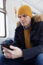 Adult Caucasian man with smartphone in a train