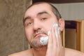 Man smears his face with white shaving foam. Preparing to shave your beard home. Close-up. Male facial care concept Royalty Free Stock Photo