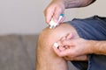 A man smears a sore knee with ointment for the joints
