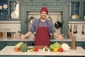 Man smile in chef hat in kitchen. Happy cook at table. Vegetables and tools ready for cooking dishes. Food preparation