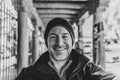 Man smiles at camera in foreground against dynamic breezeway in black and white