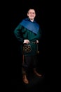 A man smiles and poses in ancient Viking clothing, hands on hips. Full height portrait. Security, protection.