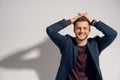 Man smiles and touches his hair. Feeling freedom. Handsome man posing in studio on white background