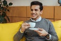 Man smiling and holding saucer and cup of coffee