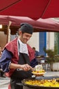 Man smiling, preparing and serving paella typical spanish meal