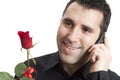 Man smiling, talking on cellphone, holding red ros Royalty Free Stock Photo