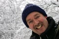 Man Smiling to the Camera while Surrounded by Snow Filled Branch Royalty Free Stock Photo