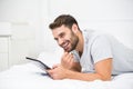 Man smiling while using digital tablet on bed Royalty Free Stock Photo