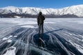 A man on smooth surface of frozen mountain lake during a strong
