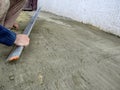 A man smooths the surface of a cement-sand mixture with an aluminium plasterers feather edge tool. Preparation of the site for Royalty Free Stock Photo