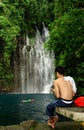 Man SMS-ing near tropical waterfall.