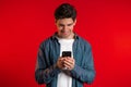 Man sms texting using app on smartphone. Handsome young guy surfing internet with mobile phone. Red studio Royalty Free Stock Photo