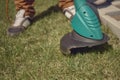 Man in sneakers and pants is mowing green grass with handheld electric lawn mower on his backyard. Gardening care Royalty Free Stock Photo