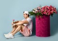 Man in sneakers shorts t-shirt is sitting at huge valentines day gift box with roses holding single flower in his hand Royalty Free Stock Photo