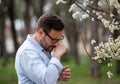 Man sneezing beside blooming tree Royalty Free Stock Photo