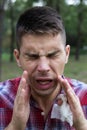 Man sneezing into Tissue. Handsome man blowing his nose in the park Royalty Free Stock Photo