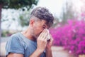 Man sneezing in a tissue outdoors. Pollen allergy, Springtime. Royalty Free Stock Photo