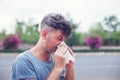 Man sneezing in a tissue outdoors. Pollen allergy, Springtime. Royalty Free Stock Photo