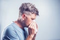 Man sneezing in a tissue outdoors. Pollen allergy, Springtime. Royalty Free Stock Photo