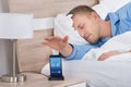 Man Snoozing Alarm On Mobile Phone Screen