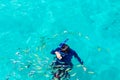 A man snorkeling in water and give a food for fish