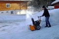 A man with a snow blower clears high snow