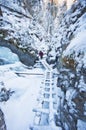 Man on snow covered wooden ladder in Sucha Bela gorge in Slovak Paradise during winter