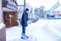 Man with snow shovel cleans sidewalks in winter during snowfall. Winter time in Europe. Young man in warm winter clothes