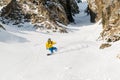 A man a snowboarder freerider descends a backcountry at high speed from a slope