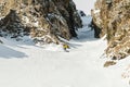 A man a snowboarder freerider descends a backcountry at high speed from a slope