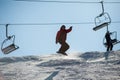 Man snowboarder jumping at ski resort against ski-lift Royalty Free Stock Photo