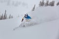 A man snowboarder at speed bends and brakes, splashing loose deep snow