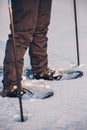 Man with snowshoe on the snow path close-up. Man in snowshoes with trekking poles in winter Royalty Free Stock Photo