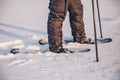 Man with snowshoe on the snow path close-up. Man in snowshoes with trekking poles in winter Royalty Free Stock Photo