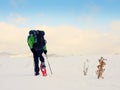 Man with snowshoes and backpack take photos by smartphone. Hiker in snowdrift