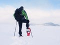 Man with snowshoes and backpack take photos by smartphone. Hiker in snowdrift