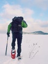 Man with snowshoes and backpack take photos by smartphone. Hiker in snowdrift