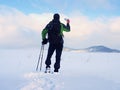 Man with snowshoes and backpack take photos by smartphone. Hiker in snowdrift