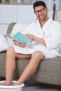man on sofa soaking feet and reading book Royalty Free Stock Photo