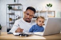 Man with son on knees working on laptop at home Royalty Free Stock Photo