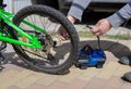 Man spins a nipple on the wheel of a children`s bicycle, after pumping a flat tire with a compressor. Royalty Free Stock Photo