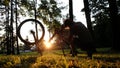 Man spins the wheel and checks the chain on an upturned bike at sunset in the park