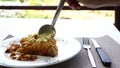 Man spooning sauce on fried battered fish in a white dish.