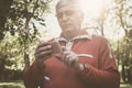 Man in sports clothing standing in park an typing on mobi