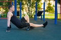 A man on the sports ground performs an exercise with a roller