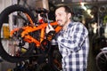 Man in sports workshop mounts bike using special tools