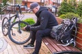 A man in sportswear is sitting on a bench next to a bicycle.